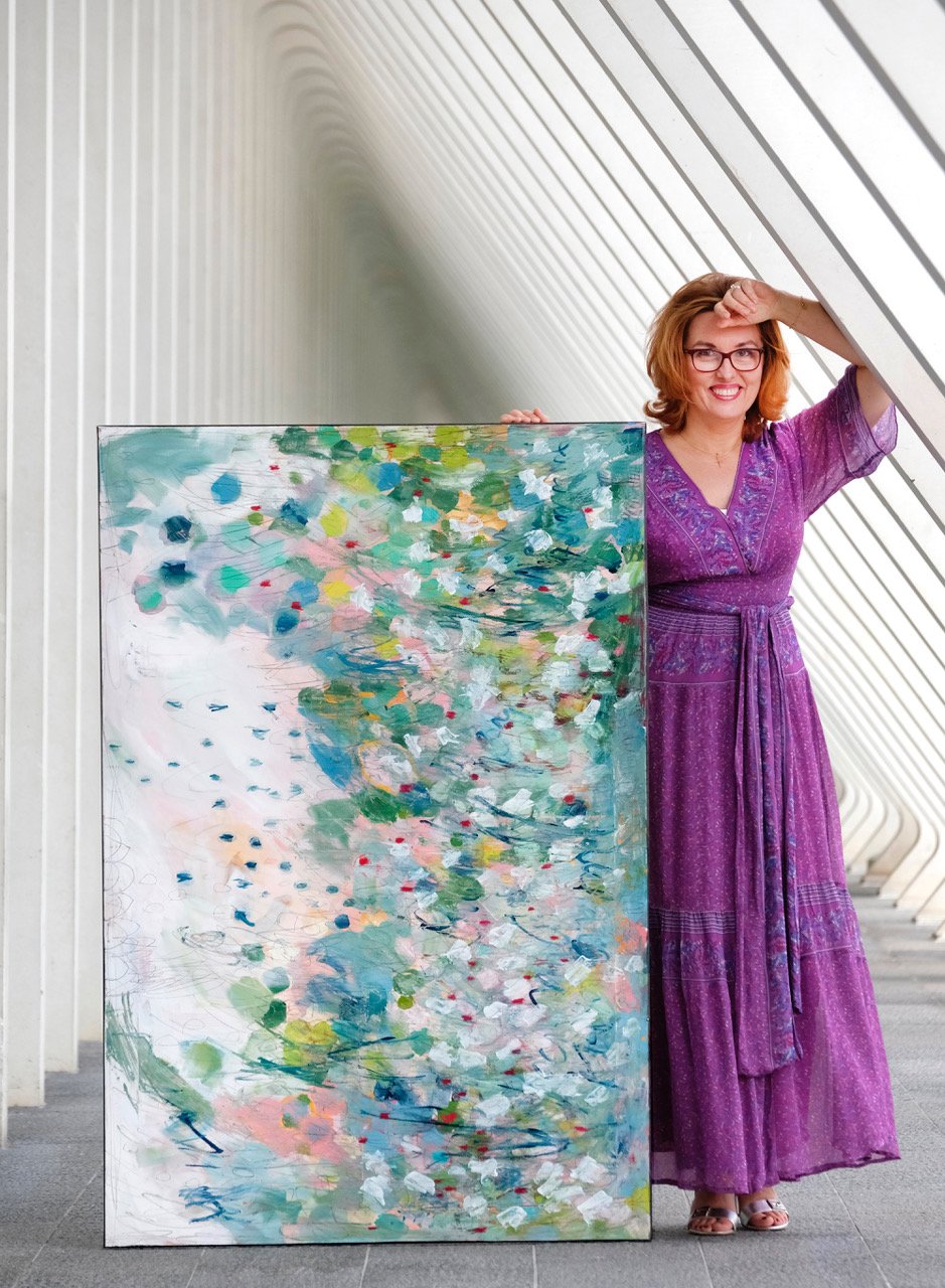 Artist Ewa Dziengielewicz standing beside one of her colourful paintings
